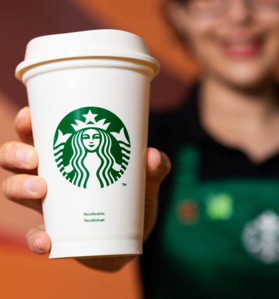 atendente do Starbucks segurando copo da rede; Zamp negocia para assumir operações da marca no Brasil