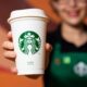 atendente do Starbucks segurando copo da rede; Zamp negocia para assumir operações da marca no Brasil