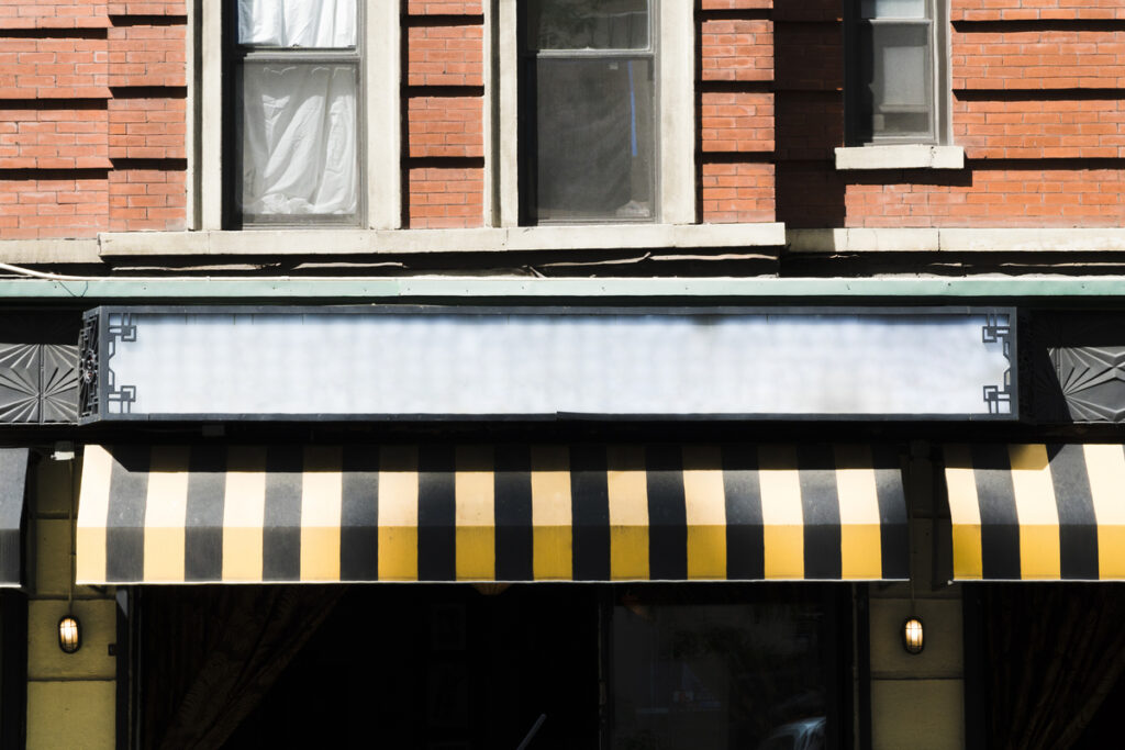 Fachada de uma loja com toldo em preto e amarelo; tributária