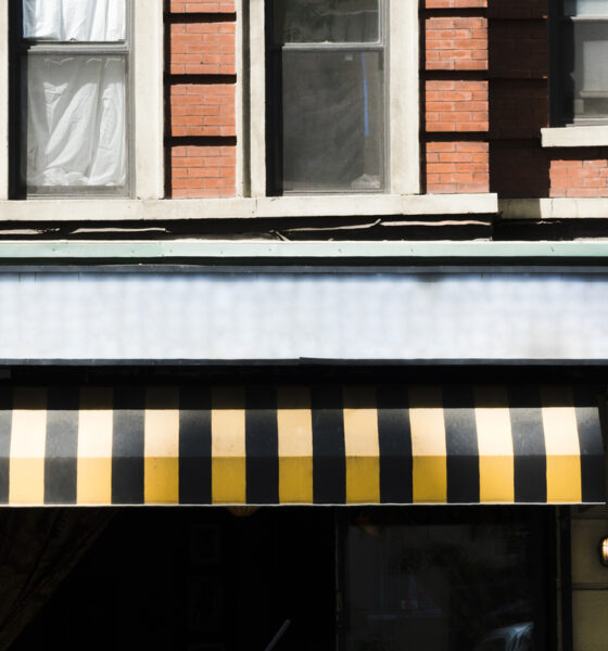 Fachada de uma loja com toldo em preto e amarelo; tributária