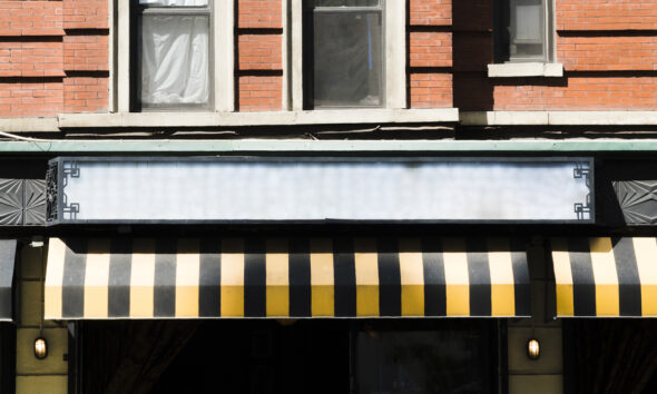 Fachada de uma loja com toldo em preto e amarelo; tributária