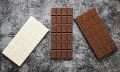 Três barras de chocolate sem casca em cima de uma mesa. Uma branca, uma mais escura e outra média.