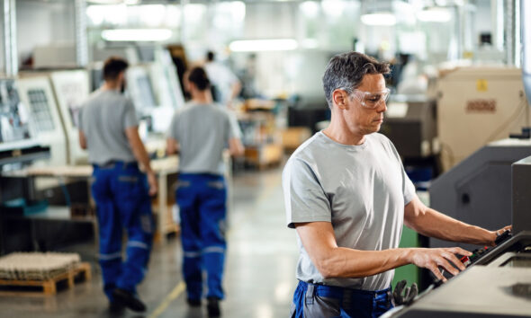homem operando maquinário em indústria; produção industrial