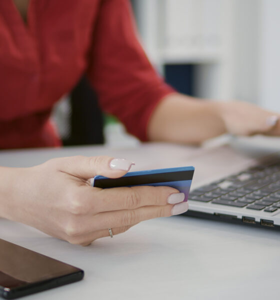 Mulher fazendo compras em ecommerce com cartão de crédito na mão