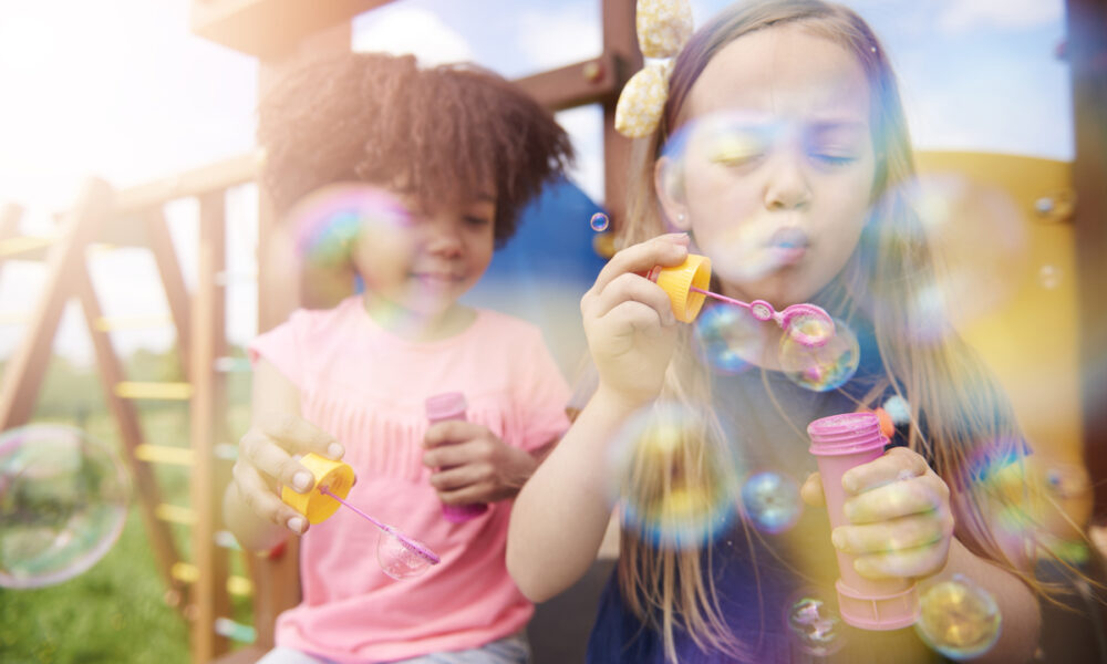 duas meninas brincando com bolha de sabão