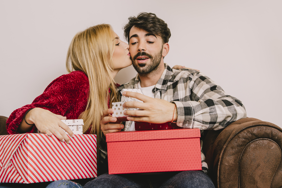 Casal hétero de namorados com presentes nas mãos.
