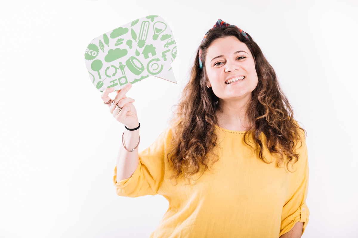 Mulher com balão de fala na mão, com desenhos verdes